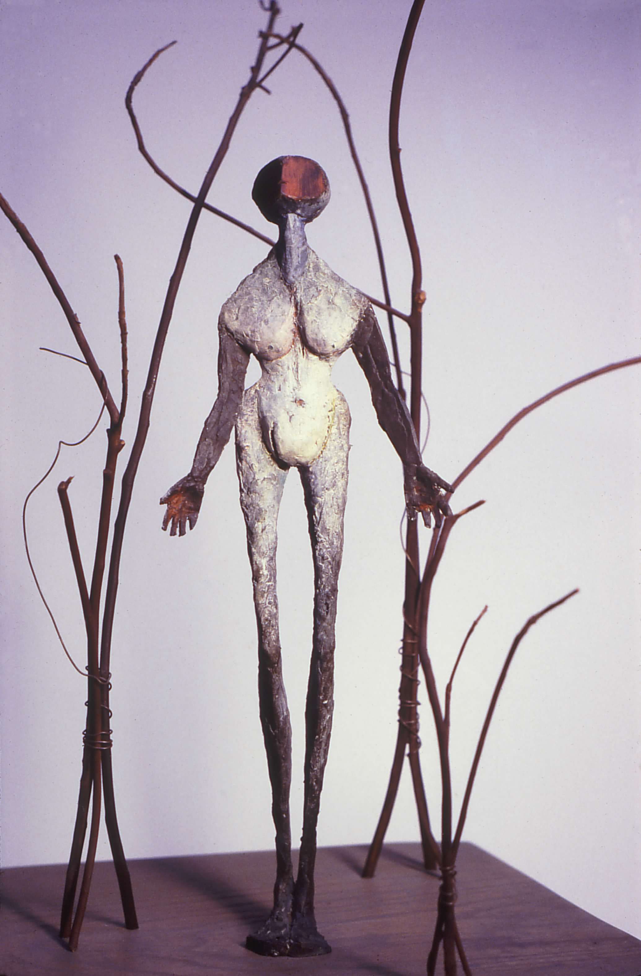 Painted bronze and madrona branches, last revision 1982, 13" x 13" x 28". This figure was originally part of a piece named Shaman. But I knew nothing of shamans. In 1980, I moved to the Oregon coast. It was beautiful. It would some day become the place where I took root. But at first it was where I had to be, where my husband's work - commercial fishing, demanded that I be. Yet I longed for the mountains, for the rhythm of the seasons and the glorious crescendos of spring and fall. I longed for the familiar.